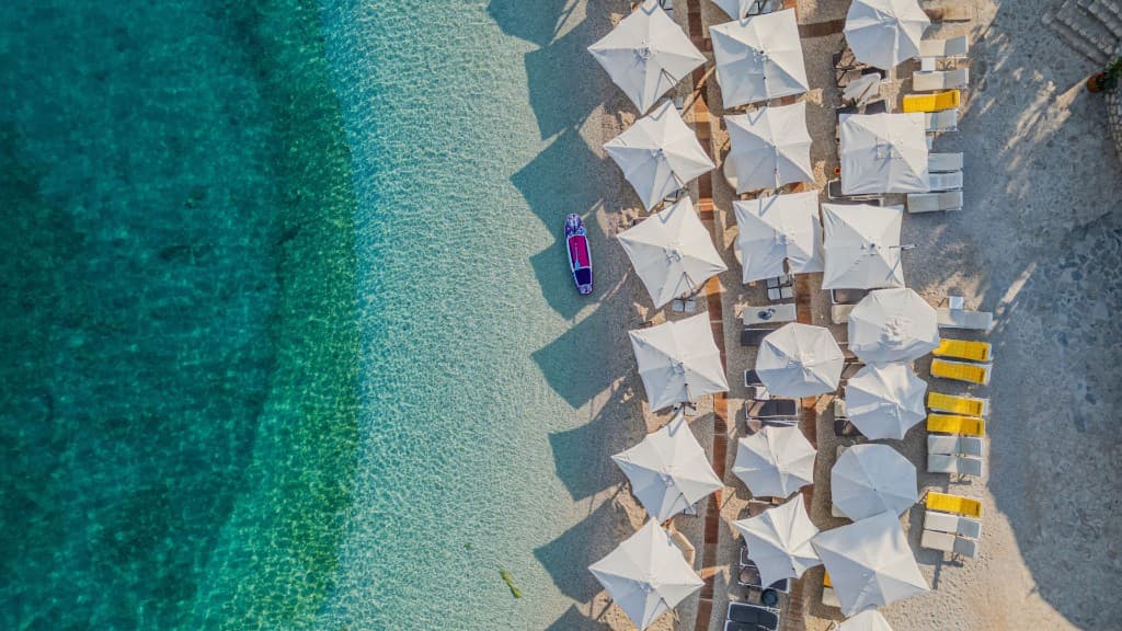 Aerial view of white beach umbrellas by turquoise water