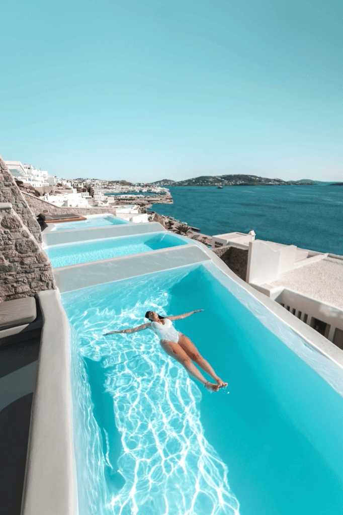 Woman floating in a turquoise pool overlooking the sea